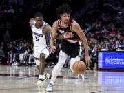 Sacramento Kings guard De'Aaron Fox, left, reaches for the ball as Portland Trail Blazers guard Shaedon Sharpe drives during the second half of an NBA basketball game in Portland, Ore., Friday, March 31, 2023.