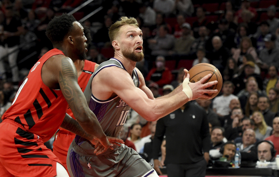 Sacramento Kings forward Domantas Sabonis, right, drives to the basket on Portland Trail Blazers forward Nassir Little, left, during the first half of an NBA basketball game in Portland, Ore., Wednesday, March 29, 2023.