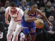 New York Knicks guard Immanuel Quickley, right, dribbles in front of Portland Trail Blazers center Jusuf Nurkic during the first half of an NBA basketball game in Portland, Ore., Tuesday, March 14, 2023.