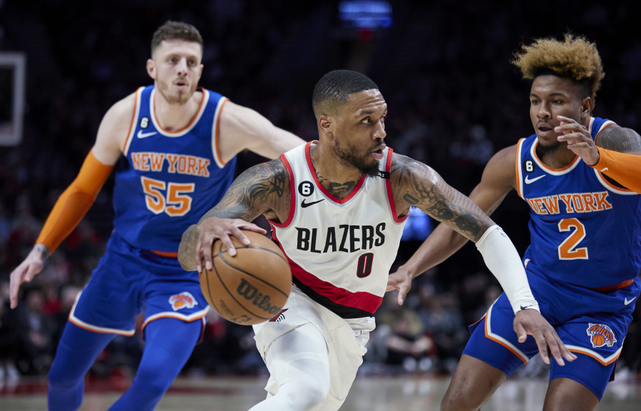 Portland Trail Blazers guard Damian Lillard, center, drives to the basket between New York Knicks guard Miles McBride, right, and center Isaiah Hartenstein during the second half of an NBA basketball game in Portland, Ore., Tuesday, March 14, 2023.