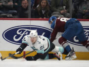 Seattle Kraken right wing Eeli Tolvanen, left, reaches for the puck after being hit by Colorado Avalanche left wing Matt Nieto in the first period of an NHL hockey game Sunday, March 5, 2023, in Denver.