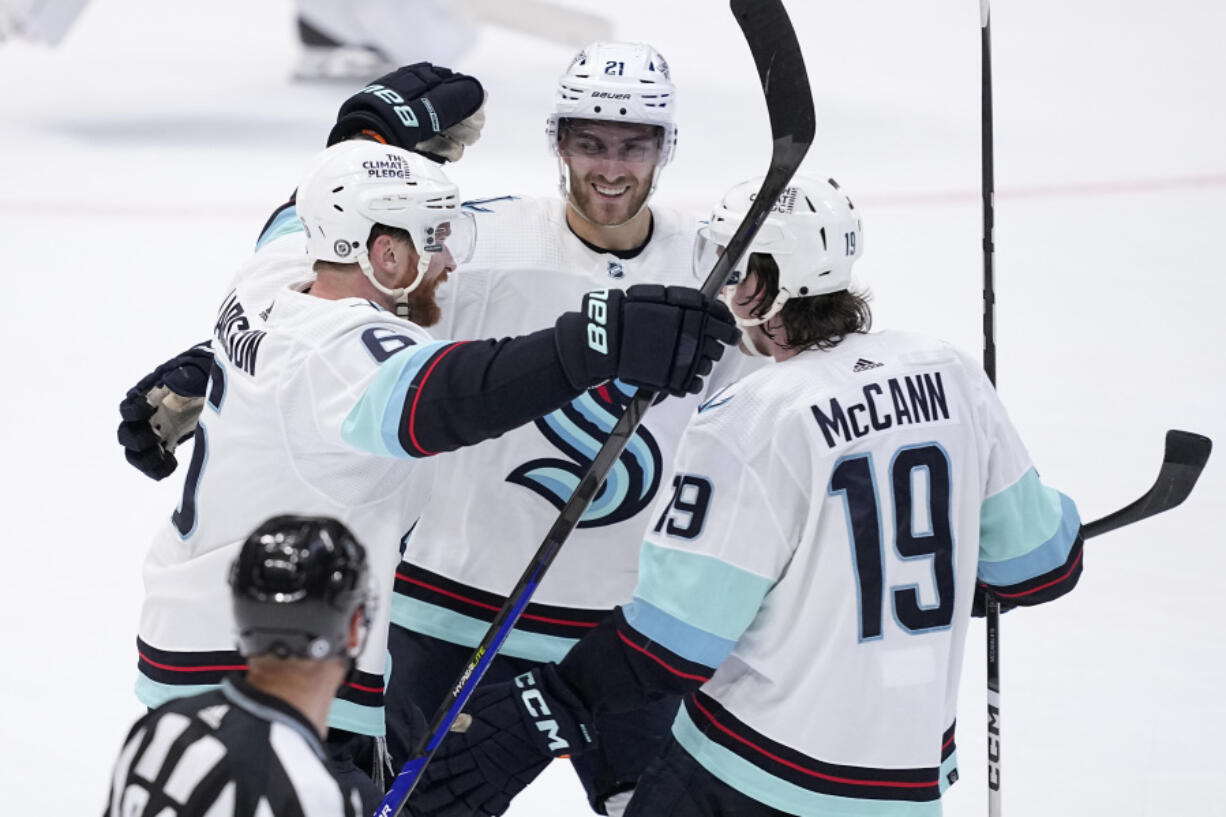 Seattle Kraken defenseman Adam Larsson (6), left wing Jared McCann (19) and center Alex Wennberg (21) celebrate after Larsson scored in overtime of an NHL hockey game against the Dallas Stars, Tuesday, March 21, 2023, in Dallas. The Kraken won 5-4.