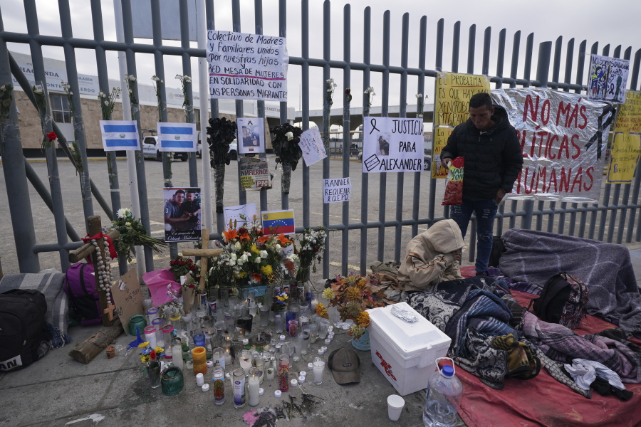 An altar with candles and photos covers the fence outside the Mexican immigration detention center that was the site of a deadly fire, as migrants wake up after spending the night on the sidewalk in Ciudad Juarez, Mexico, Thursday, March 30, 2023.