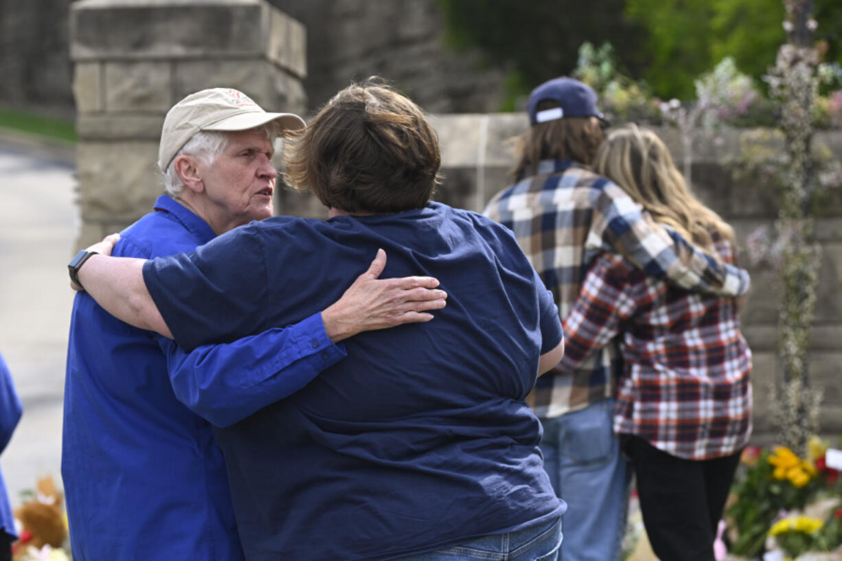 People console each other at an entry to Covenant School, Tuesday, March 28, 2023, in Nashville, Tenn., which has become a memorial to the victims of Monday's school shooting.