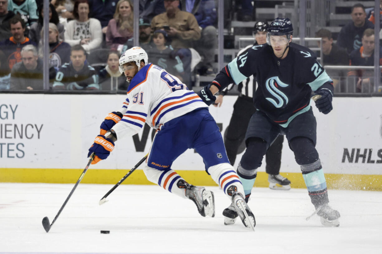 Edmonton Oilers left wing Evander Kane (91) trips on the stick of Seattle Kraken defenseman Jamie Oleksiak (24) during the third period of an NHL hockey game, Saturday, March 18, 2023, in Seattle.
