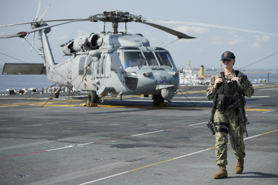A U.S. Navy personnel walks past a helicopter onboard USS America (LHA 6) during a scheduled port visit in Manila, Philippines on Tuesday, March 21, 2023. Capt.