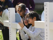 Children sign a cross at an entry to Covenant School, Tuesday, March 28, 2023, in Nashville, Tenn., which has become a memorial to the victims of Monday's deadly school shooting.