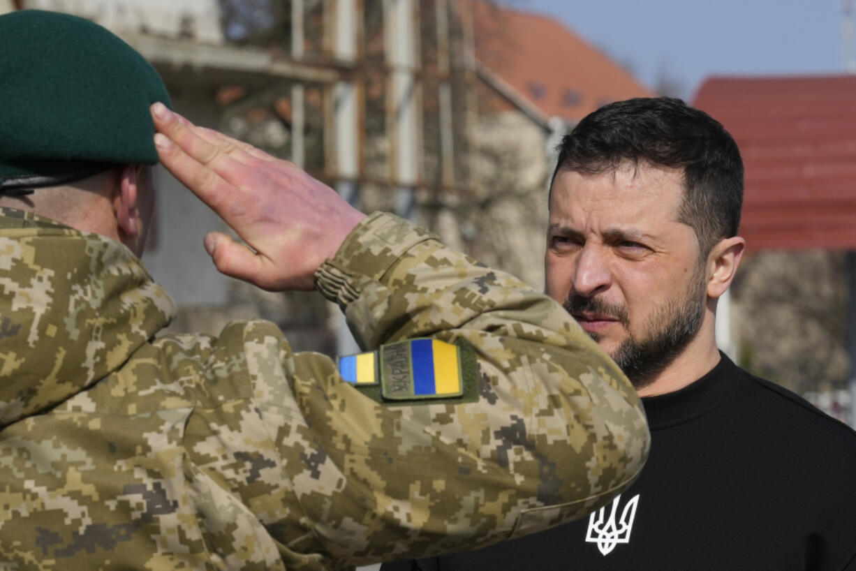 A serviceman salutes Ukrainian President Volodymyr Zelenskyy as he is awarded a medal in Trostianets in the Sumy region of Ukraine, Tuesday March 28, 2023.