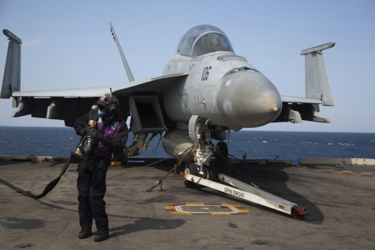 A crew member works next to a U.S. Navy F-18 Super Hornets on the flight deck of the USS Nimitz off the coast of Busan, South Korea, Monday, March 27, 2023. The nuclear-powered U.S. aircraft carrier and its battle group began exercises with South Korean warships on Monday, hours after North Korea fired two short-range ballistic missiles in an apparent protest of the allies' expanding drills.