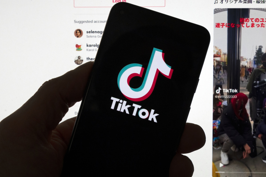 FILE - The TikTok logo is seen on a mobile phone in front of a computer screen which displays the TikTok home screen, Saturday, March 18, 2023, in Boston.