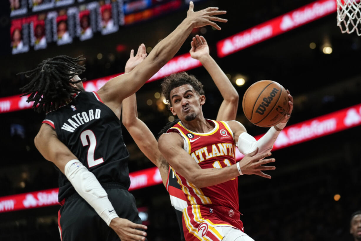 Atlanta Hawks guard Trae Young (11) passes the ball around Portland Trail Blazers' Trendon Watford (2) during the first half of an NBA basketball game Friday, March 3, 2023, in Atlanta.