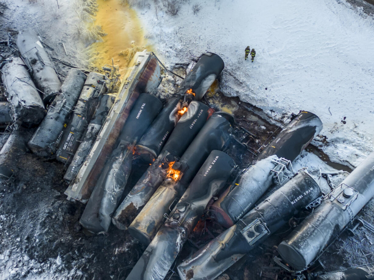 Firefighters stand near piled up train cars, near Raymond, Minn., Thursday, March 30, 2023, the morning after a BNSF freight train derailed. Authorities say a train hauling ethanol and corn syrup derailed and caught fire and residents within 1/2 mile of the crash were ordered to evacuate from their homes.