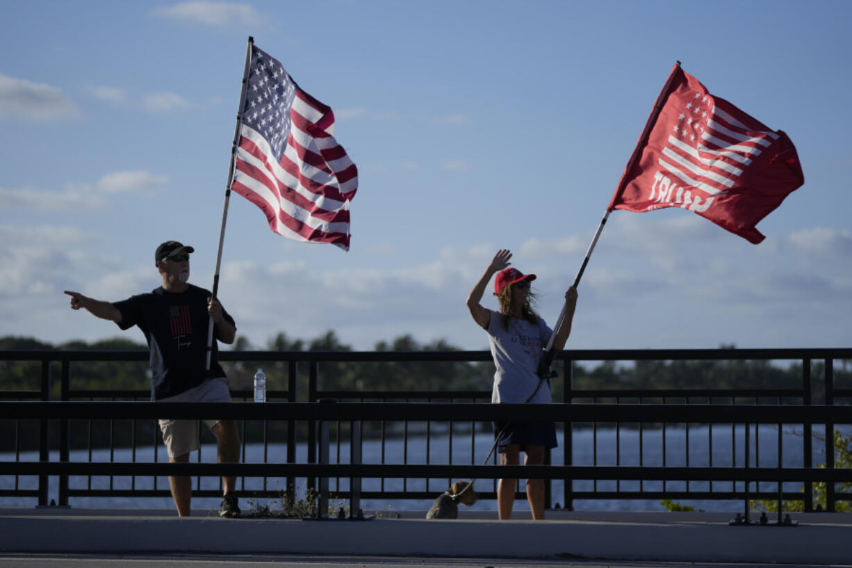 People acknowledge supportive honks from passing cars as they show support for former President Donald Trump a day after he was indicted by a Manhattan grand jury, Thursday, March 30, 2023, near Trump's Mar-a-Lago estate in Palm Beach, Fla.