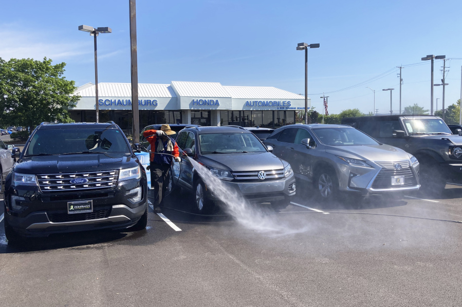 A worker washes used cars for sale outside of a Honda certified used car dealership Tuesday, July 19, 2022, in Schaumburg, Ill. (AP Photo/Nam Y.
