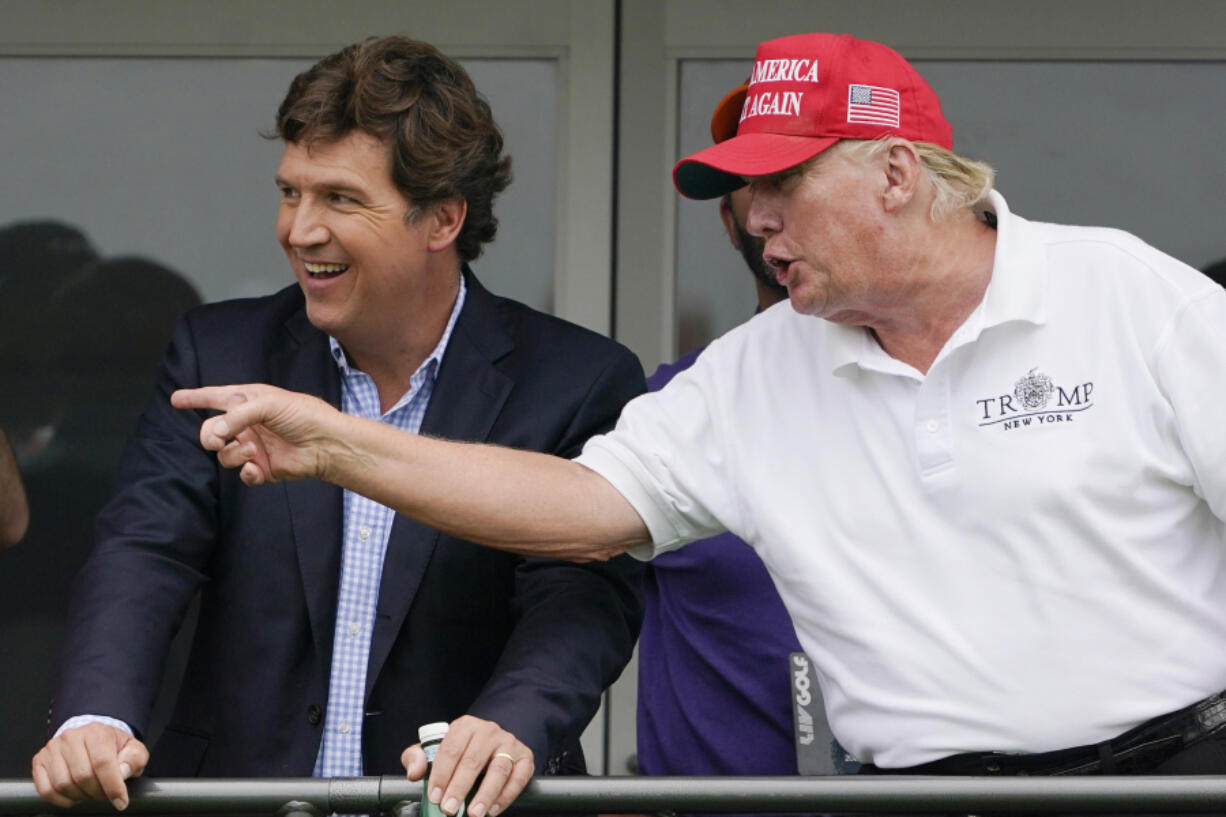 Tucker Carlson, left, and former President Donald Trump, talk while watching golfers on the 16th tee during the final round of the LIV Golf Invitational at Trump National in Bedminster, N.J., July 31, 2022. A defamation lawsuit against Fox News is revealing blunt behind-the-scenes opinions by its top figures about Donald Trump, including a Tucker Carlson text message where he said "I hate him passionately." Carlson's private conversation was revealed in court papers at virtually the same time as the former president was hailing the Fox News host on social media for a "great job" for using U.S. Capitol security video to produce a false narrative of the Jan. 6, 2021, insurrection.