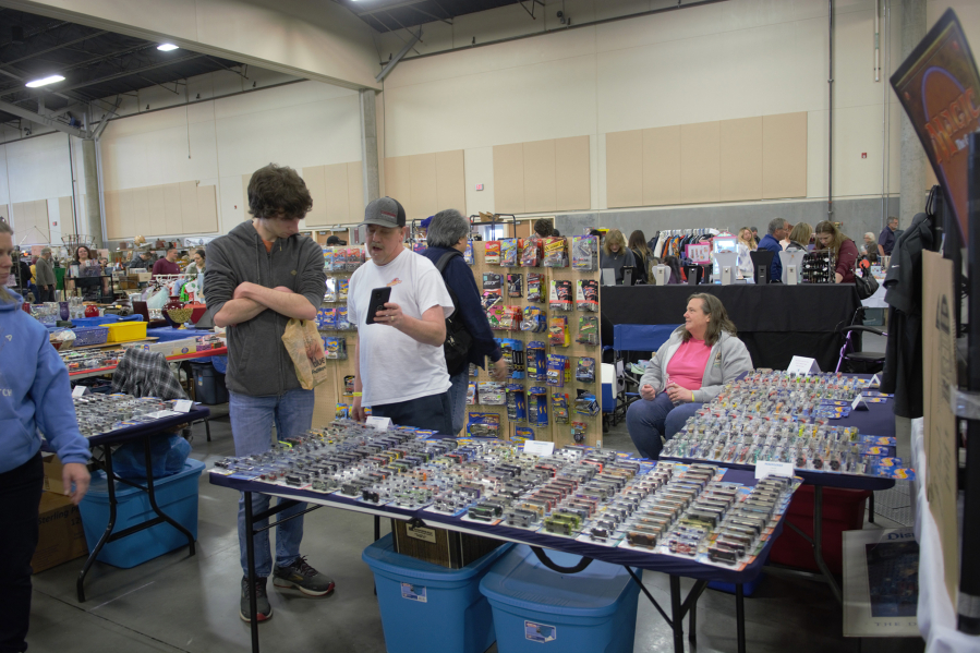 Travis Zimmerly, center, shows a prospective buyer a rare Hot Wheels car he's got in his vast collection Saturday at the Northwest's Largest Garage Sale at the Clark County Event Center at the Fairgrounds.
