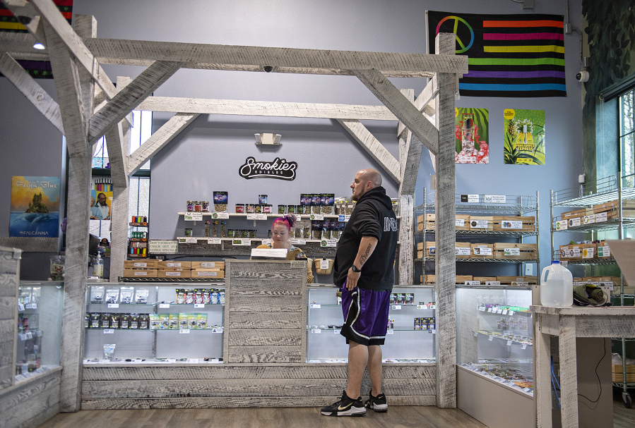Budtender Tabbie Tirey, left, chats with Brandon Nickell, head of security, while working at Orchards Cannabis Market.