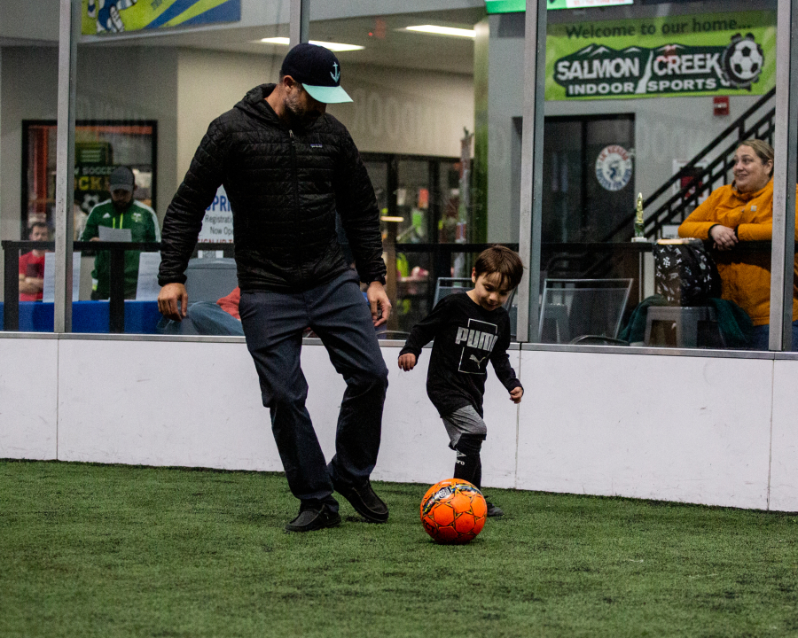 Brett Seifried of Ridgefield kicks a soccer ball with his son, Archer, 5, at Salmon Creek Indoor Sports Arena on a recent Sunday. Archer participates in Salmon Creek TOPSoccer, an inclusive team for kids with disabilities. Archer, who has cerebral palsy, can control his body much better after undergoing selective dorsal rhizotomy surgery at Seattle Children's Hospital in 2022.