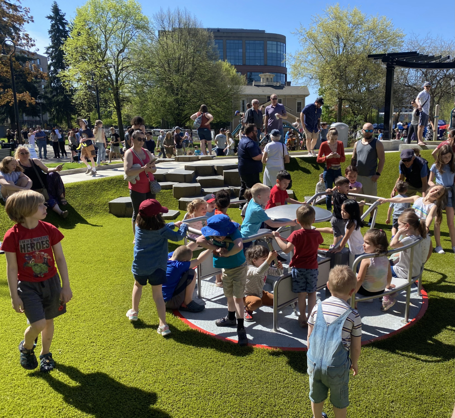 Children play on the merry-go-round at the newly reopened Esther Short Park in downtown Vancouver. The merry-go-round is at ground level and has seats to make it more accessible to kids with different abilities.
