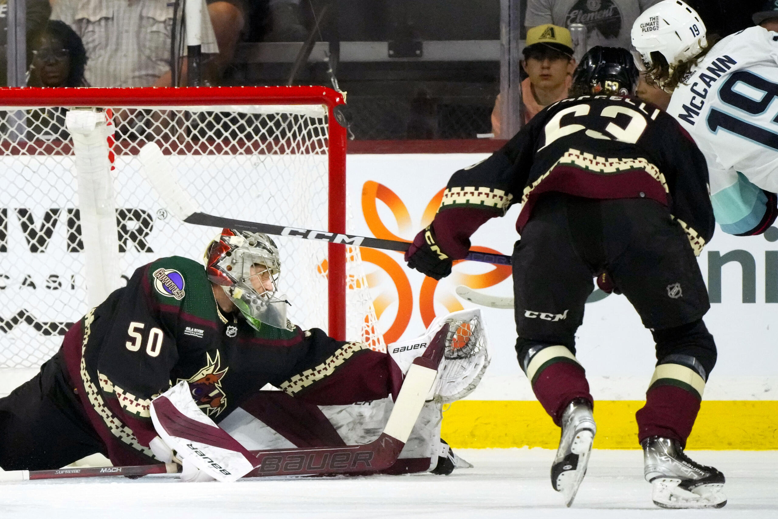 Seattle Kraken left wing Jared McCann (19) has his shot blocked by Arizona Coyotes goaltender Ivan Prosvetov (50) as Coyotes left wing Matias Maccelli, second from right, looks on during the first period of an NHL hockey game Monday, April 10, 2023, in Tempe, Ariz. (AP Photo/Ross D.