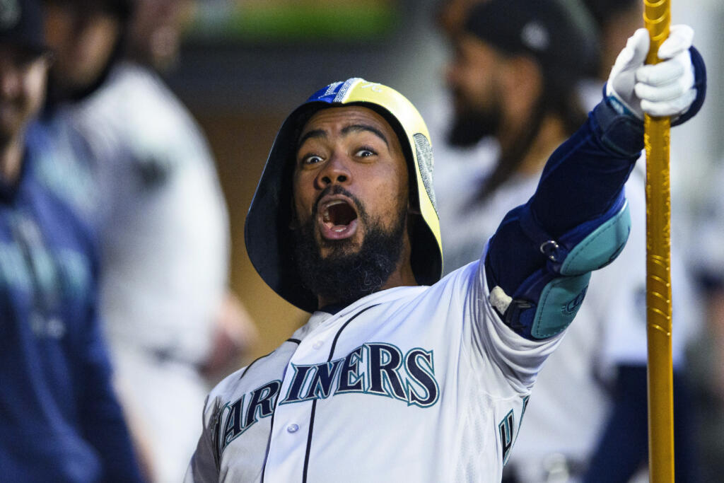 Seattle Mariners' Teoscar Hernandez celebrates his home run against the St. Louis Cardinals with a helmet and trident in the dugout during the fourth inning of a baseball game Friday, April 21, 2023, in Seattle.