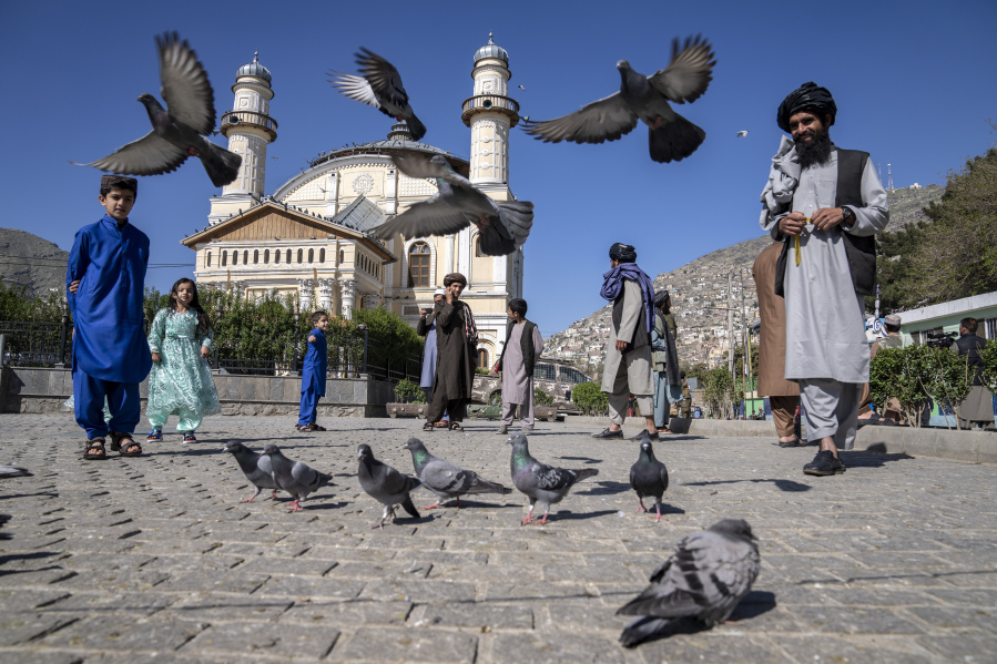 Afghan people walk pass the Shah-Do Shamshira Mosque during the first day of Eid al-Fitr in Kabul, Afghanistan, Friday, April 21, 2023.