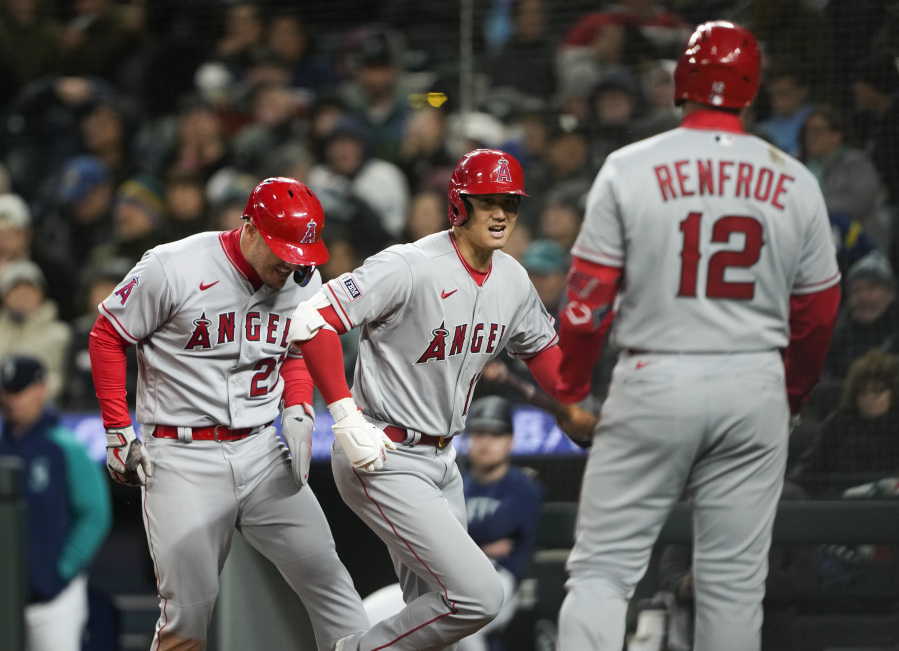 Los Angeles Angels designated hitter Shohei Ohtani, center, celebrates after his two-run home run against the Seattle Mariners which also scored teammate Mike Trout, left, as Hunter Renfroe (12) looks on in the fifth inning during a baseball game Monday, April 3, 2023, in Seattle.