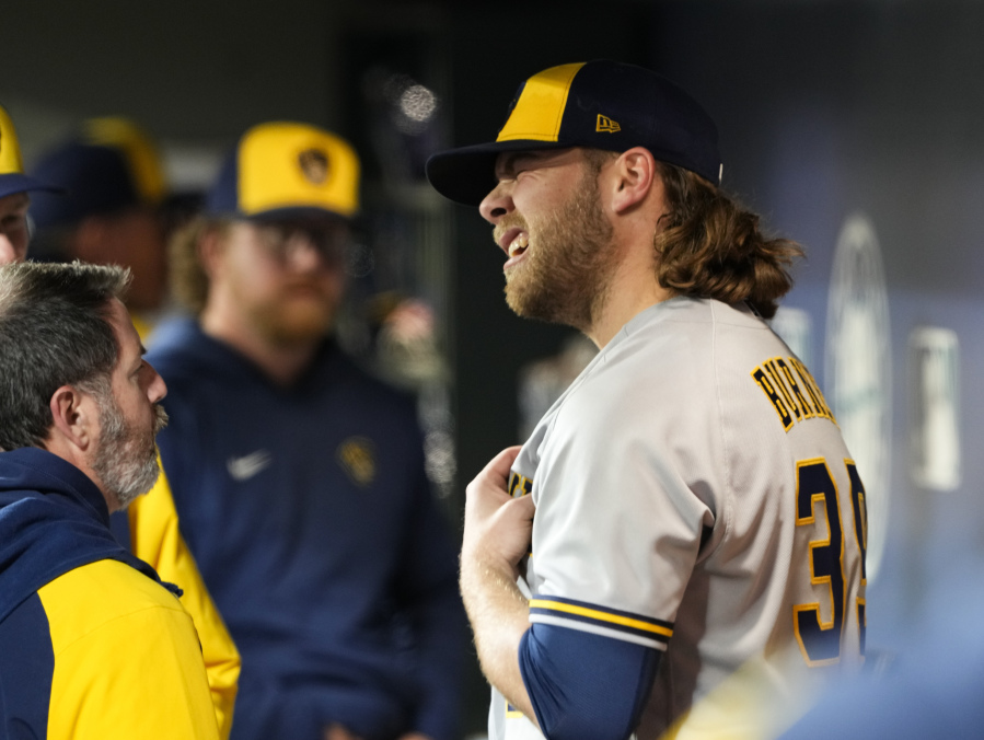 Milwaukee Brewers starting pitcher Corbin Burnes stands in the dugout as he talks with Brewers staff after leaving a baseball game against the Seattle Mariners with an apparent injury during the sixth inning Monday, April 17, 2023, in Seattle.