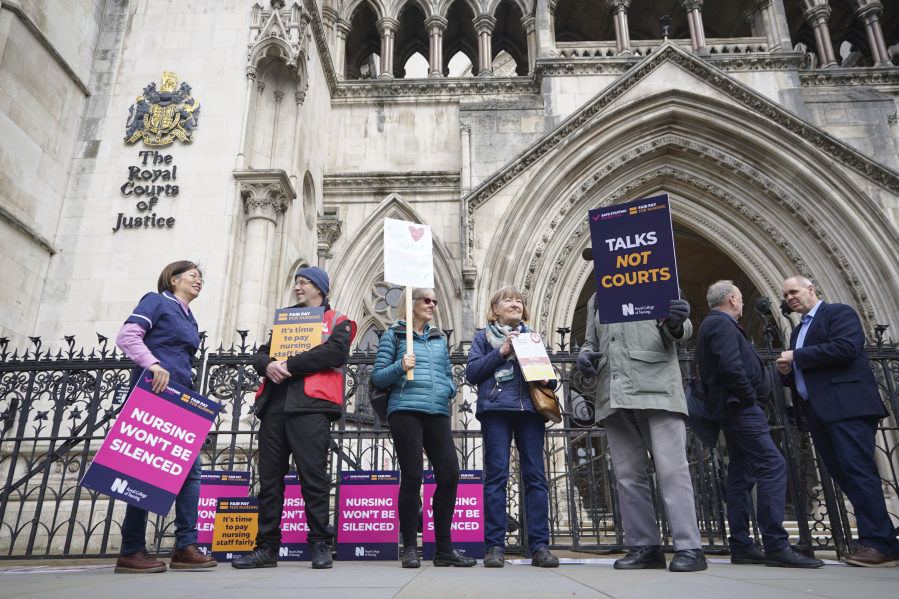 Nurses stand outside the High Court in central London, where the government is bringing a challenge over the planned strike action by the Royal College of Nurses (RCN) in the long-running dispute over pay, in London, Thursday April 27, 2023.