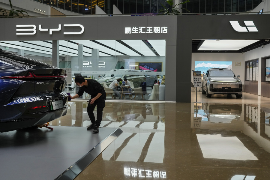 A worker wipes a Rising F7 car model at a floor section selling various Chinese-made electric car brands inside a shopping mall in Beijing, Tuesday, April 4, 2023. Furious at U.S. efforts that cut off access to technology to make advanced computer chips, China's leaders appear to be struggling to figure out how to retaliate without hurting their own ambitions in telecoms, artificial intelligence and other industries.