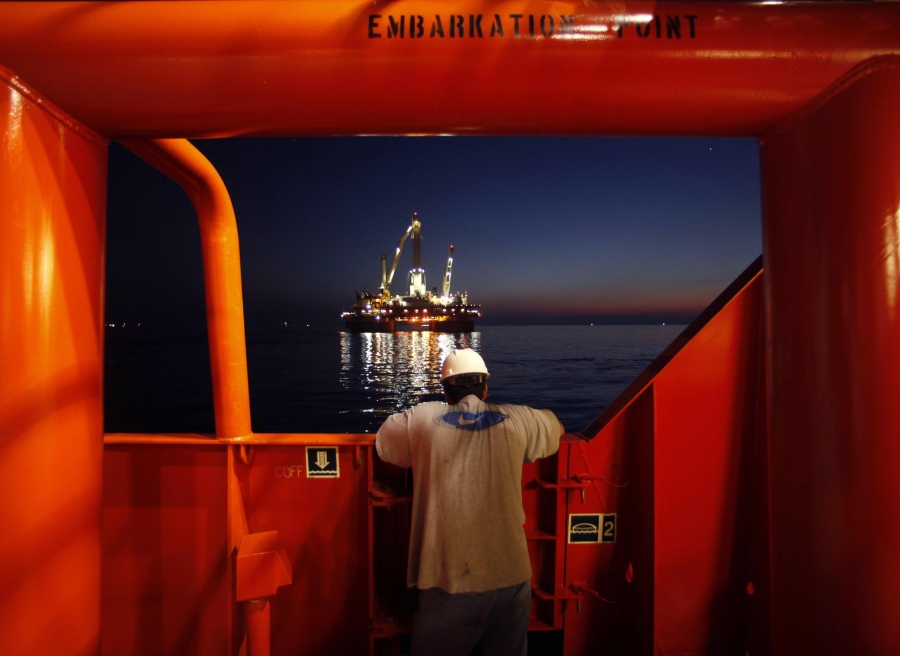 FILE - Wilson Ruiz, a crew member of the Joe Griffin, looks out at the oil slick as a containment vessel onboard positioned near the Q4000, background center, being lowered over the oil leak, at the site of the BP Deepwater Horizon offshore oil rig collapse in the Gulf of Mexico on May 6, 2010. A new National Academy of Science study says that 13 years after a massive BP oil spill fouled the Gulf of Mexico, regulators and industry have reduced some risks in deep water exploration in the gulf but some troublesome safety issues persist.
