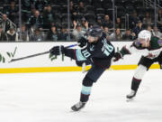 Seattle Kraken center Matty Beniers, left, shoots and scores next to Arizona Coyotes defenseman Juuso Valimaki during the third period of an NHL hockey game Thursday, April 6, 2023, in Seattle. The Kraken won 4-2 to clinch a playoff spot for the first time in franchise history.