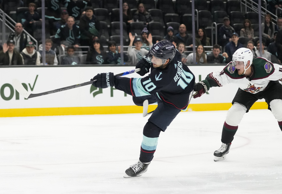 Seattle Kraken center Matty Beniers, left, shoots and scores next to Arizona Coyotes defenseman Juuso Valimaki during the third period of an NHL hockey game Thursday, April 6, 2023, in Seattle. The Kraken won 4-2 to clinch a playoff spot for the first time in franchise history.