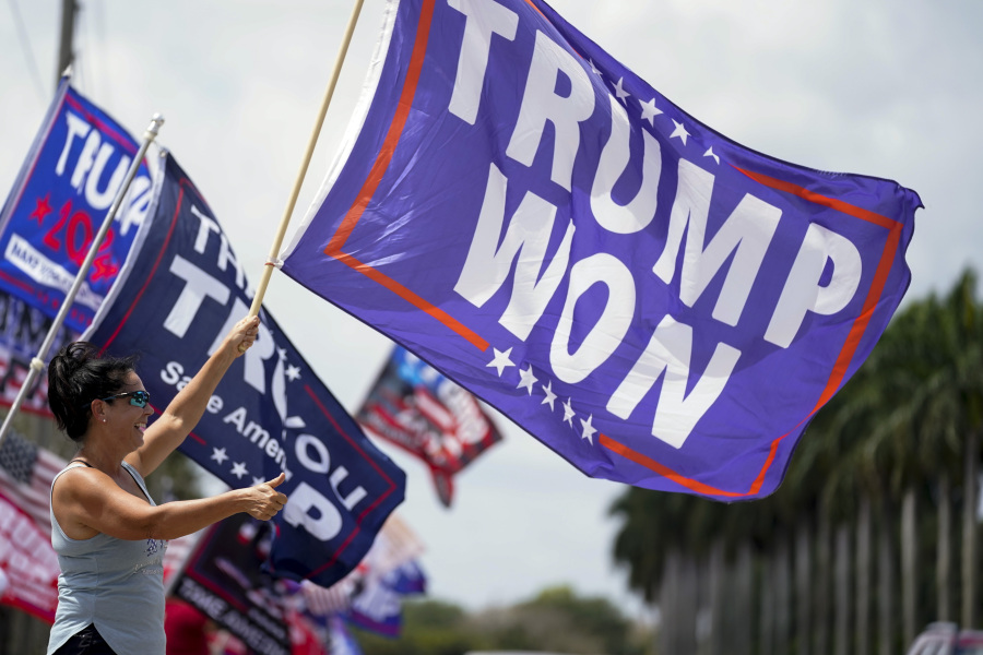 FILE - Supporters of former President Donald Trump wave flags in support of Trump outside Trump International Golf Club, Saturday, April 1, 2023, in West Palm Beach, Fla.