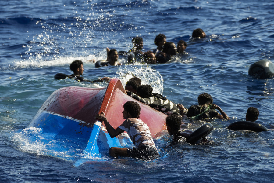 FILE - Migrants swim next to their overturned wooden boat during a rescue operation by Spanish NGO Open Arms at south of the Italian Lampedusa island at the Mediterranean sea, Aug. 11, 2022. European Union lawmakers approved on Thursday, April 20, 2023 a series of proposals aimed at ending the years-long standoff over how best to manage migration, a conundrum that has provoked one of the bloc's biggest political crises.