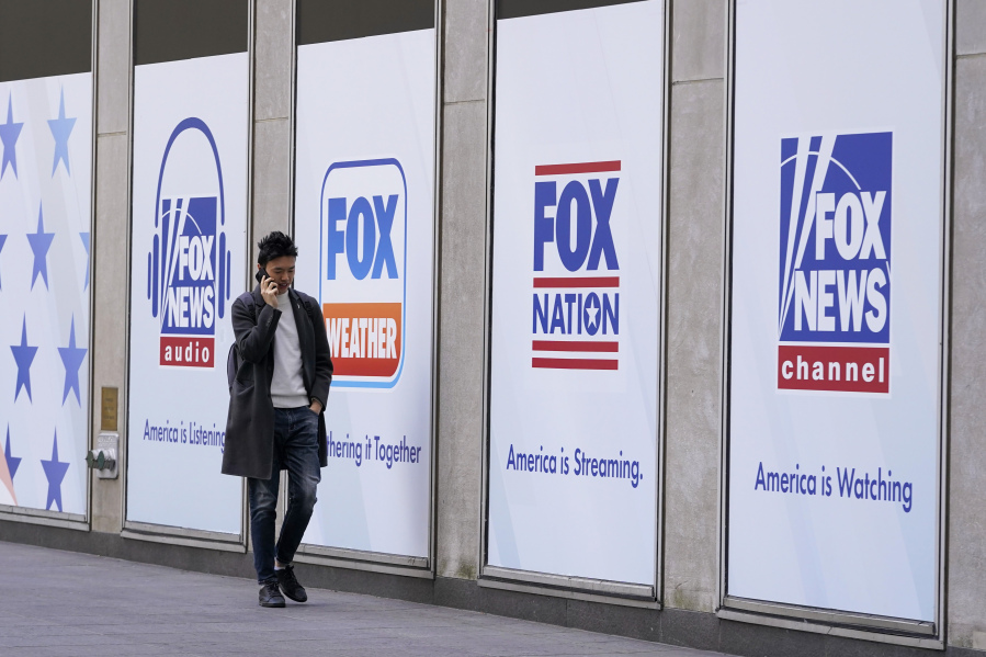 File - A man walks past the News Corp. and Fox News headquarters on April 19, 2023, in New York. Fox News agreed Wednesday, April 26, to hand over reams of documents produced during the just-settled defamation lawsuit between Dominion Voting Machines to another voting technology firm, Smartmatic, which in a $2.7 billion suit accuses the cable news giant of damaging its reputation because of the network's promotion of lies about the 2020 election.