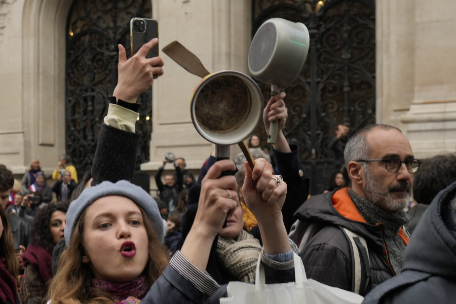 FILE - People bang pots and pans while French President Emmanuel Macron speaks in a televised address to the nation, Monday, April 17, 2023 in Paris. A country renowned for its cuisine is turning to pots and pans to express discontent with French President Emmanuel Macron's pension reforms. French demonstrations against raising the retirement age from 62 to 64 have morphed from lobbing paving stones, dodging tear gas and brandishing banners to something nearer the soul of the gastronomic nation: Making noise by banging kitchen saucepans.