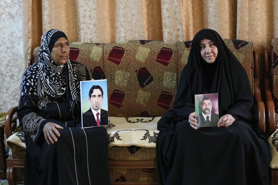 Nidal Ali, right, and Nawal Sweidan hold photos of their missing sons in Mahmoudiya, south of Baghdad, Iraq, Tuesday, March 28, 2023. Their sons were both kidnapped by extremist groups in 2014. Though active conflict in Iraq has largely subsided, many are still waiting to learn the fate of missing loved ones who disappeared during the US invasion, the subsequent civil war, or during the war against the Islamic State.