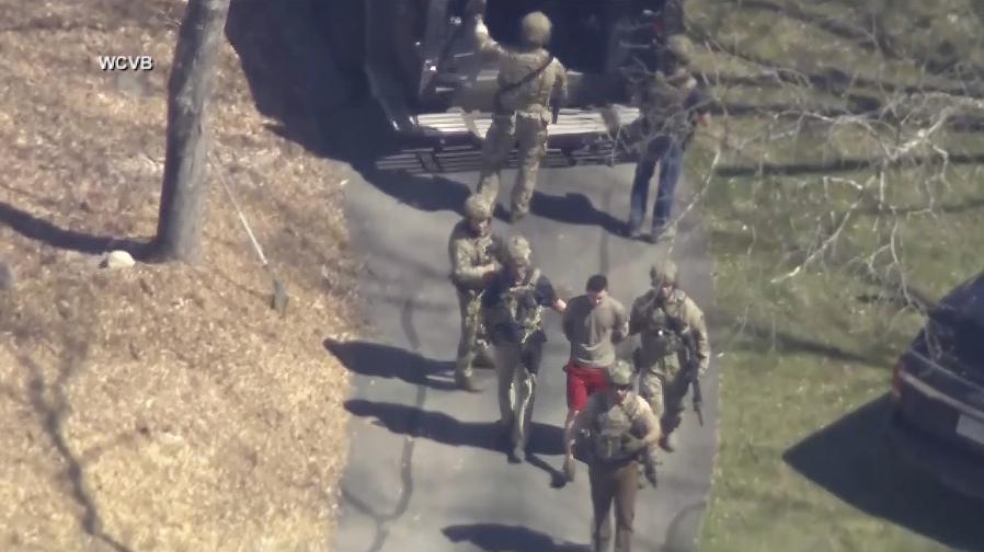FILE - This image made from video provided by WCVB-TV, shows Jack Teixeira, in T-shirt and shorts, being taken into custody by armed tactical agents on Thursday, April 13, 2023, in Dighton, Mass. A judge is expected to hear arguments Thursday, April 27, over whether Teixeira, accused of leaking highly classified military documents about the Ukraine war and other issues, should remain in jail while he awaits trial.