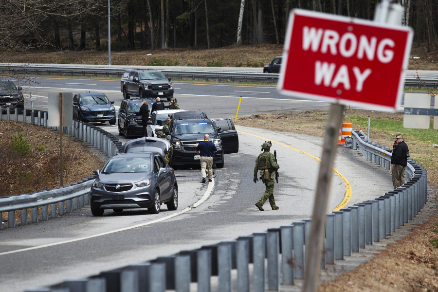 Members of law enforcement investigate a scene where people were injured in a shooting on Interstate 295 in Yarmouth, Maine, Tuesday, April 18, 2023. Gunfire that erupted on the busy highway in Maine is linked to a second crime scene where people have been found dead in a home about 25 miles away in the town of Bowdoin, Maine, state police said Tuesday.