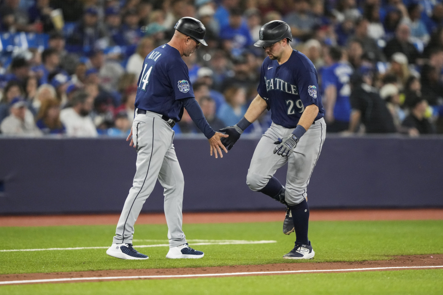 Seattle Mariners' Cal Raleigh (29), right, celebrates after his home run against the Toronto Blue Jays with third base coach Manny Acta (14) during eighth-inning baseball game action in Toronto, Sunday, April 30, 2023.