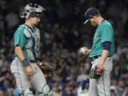Seattle Mariners starting pitcher Chris Flexen, right, looks down as he listens to catcher Cal Raleigh after Chicago Cubs' Nelson Velazquez hit a grand slam during the third inning of a baseball game in Chicago, Tuesday, April 11, 2023. (AP Photo/Nam Y.