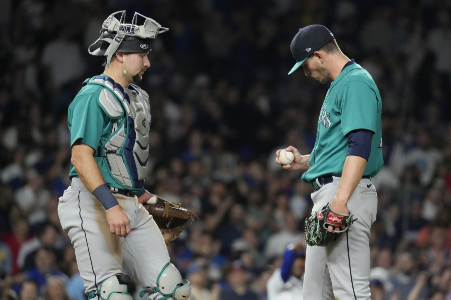 Seattle Mariners starting pitcher Chris Flexen, right, looks down as he listens to catcher Cal Raleigh after Chicago Cubs' Nelson Velazquez hit a grand slam during the third inning of a baseball game in Chicago, Tuesday, April 11, 2023. (AP Photo/Nam Y.