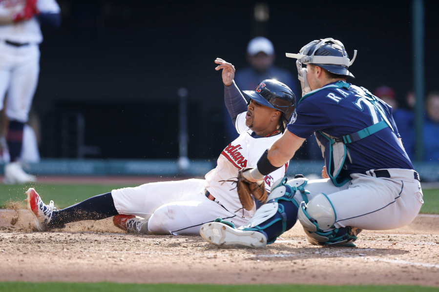 Cleveland Guardians' Jose Ramirez, left, scores the game winning run past Seattle Mariners catcher Cal Raleigh on a fielders choice by Josh Bell during the 12th inning of a baseball game, Sunday, April 9, 2023, in Cleveland.
