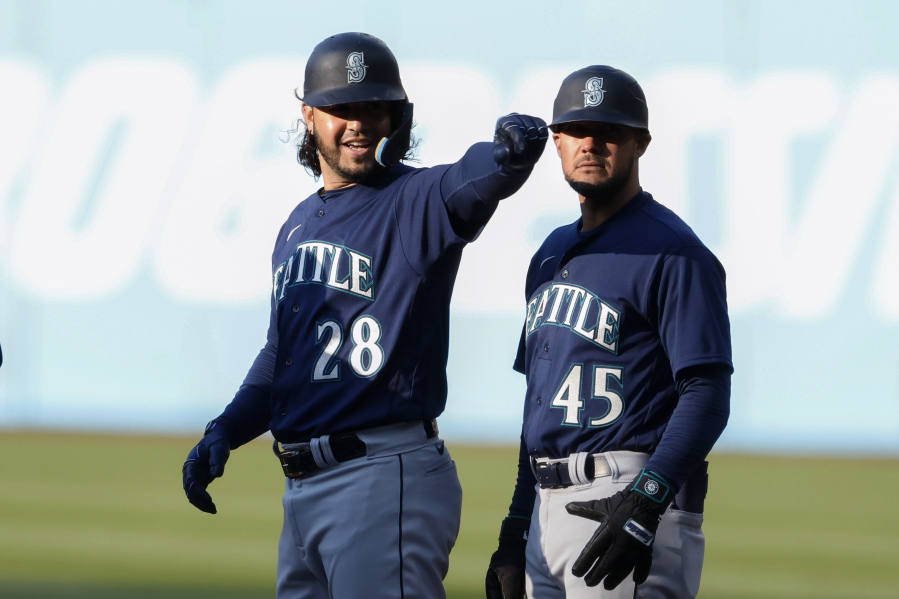 Seattle Mariners' Eugenio Suarez (28) celebrates first base coach Kristopher Negr?n (45) after hitting an RBI single off Cleveland Guardians starting pitcher Cal Quantrill during the first inning of a baseball game Saturday, April 8, 2023, in Cleveland.