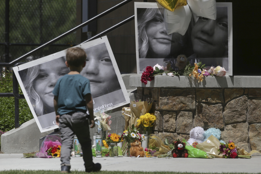 FILE - A boy looks at a memorial for Tylee Ryan and Joshua "JJ" Vallow in Rexburg, Idaho, on June 11, 2020. A mother charged with murder in the deaths of her two children is set to stand trial in Idaho. The proceedings against Lori Vallow Daybell beginning Monday, April 3, 2023, could reveal new details in the strange, doomsday-focused case.