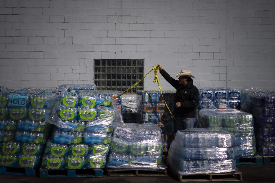Volunteer David Graham organizes pallets of bottles at a water distribution sight at Brittain Chevrolet in East Palestine, Ohio, Tuesday, March 7, 2023. The railroad says testing shows drinking water is safe, though it's establishing a fund for long-term drinking water protection.