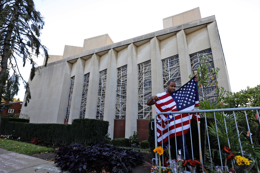FILE--A man places an American flag outside the Tree of Life synagogue in Pittsburgh on Sunday, Oct. 27, 2019, the first anniversary of the shooting at the synagogue, that killed 11 worshippers. (AP Photo/Gene J.