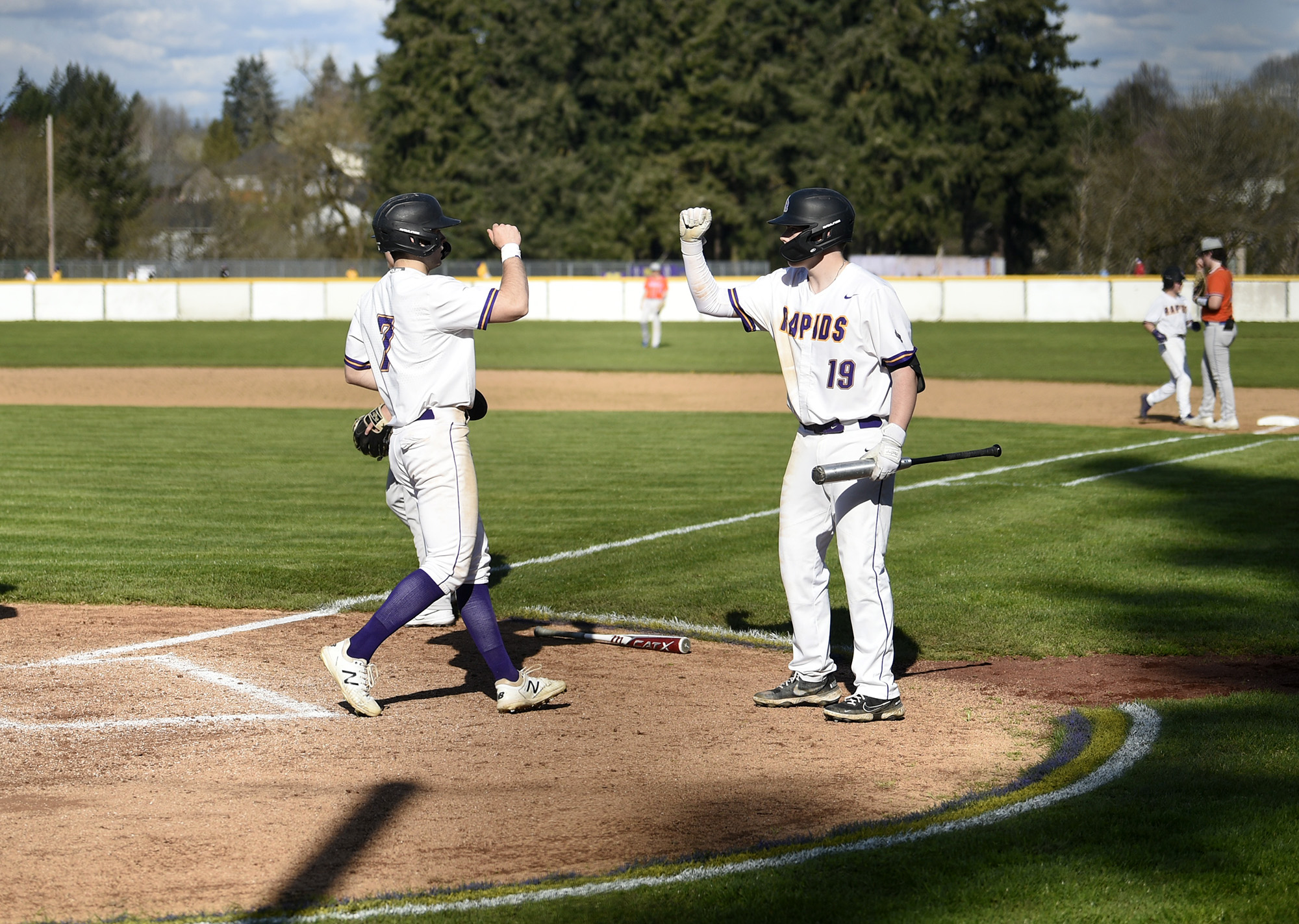 Columbia River’s Chris Parkin (7) is greeted by Zayne Boyes (19) after scoring on a single by Noah Larson during the Rapids' 6-3 win over Ridgefield in a 2A Greater St. Helens League baseball game at Columbia River on Friday, April 14, 2023.
