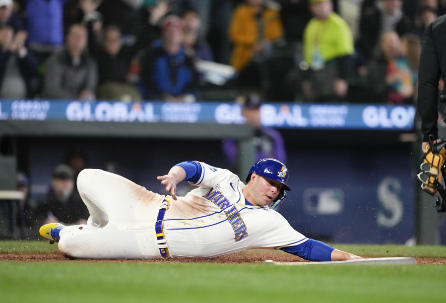 Seattle Mariners' Ty France slides to score on a single by Jarred Kelenic against the Colorado Rockies during the sixth inning of a baseball game Sunday, April 16, 2023, in Seattle.